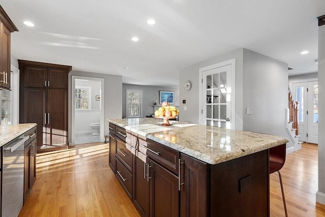 kitchen with a kitchen breakfast bar, a kitchen island, light hardwood / wood-style flooring, and light stone countertops