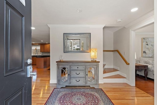 entrance foyer with recessed lighting, light wood-type flooring, baseboards, and ornamental molding