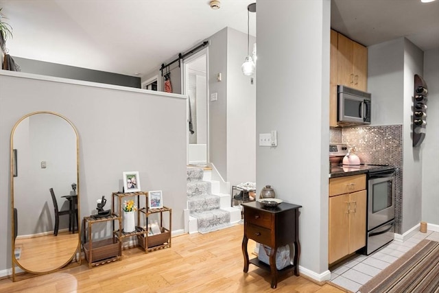 350 W 4th St Unit 103, Boston, MA 02127 - kitchen with stainless steel appliances, a barn door, dark countertops, light wood finished floors, and backsplash