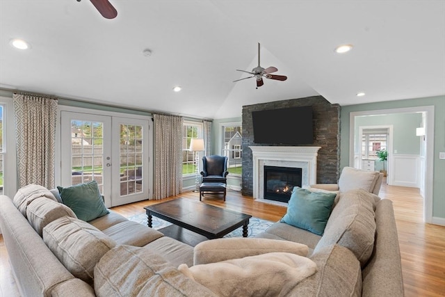 living area featuring french doors, a fireplace with flush hearth, ceiling fan, and light wood-type flooring