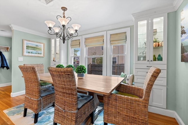 dining space featuring crown molding, baseboards, a notable chandelier, and light wood finished floors