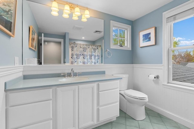full bathroom with visible vents, vanity, wainscoting, toilet, and tile patterned floors