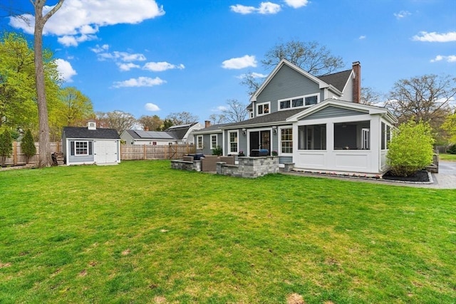 back of house featuring a storage unit, a sunroom, a fenced backyard, a chimney, and an outdoor living space
