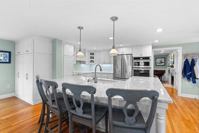kitchen with light wood-style floors, a sink, white cabinetry, and stainless steel appliances