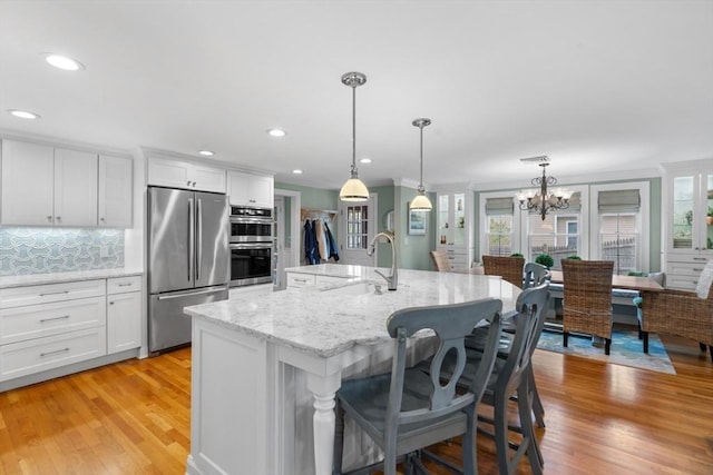 kitchen with stainless steel appliances, a breakfast bar, white cabinetry, and a sink
