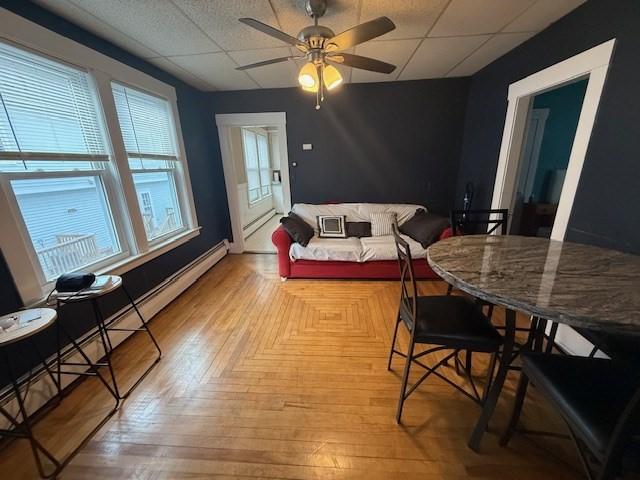 dining room featuring a drop ceiling, ceiling fan, and light wood-type flooring