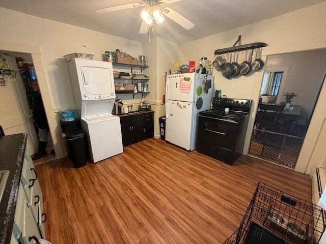 kitchen featuring wood-type flooring, stacked washer and dryer, white fridge, ceiling fan, and black range with electric stovetop