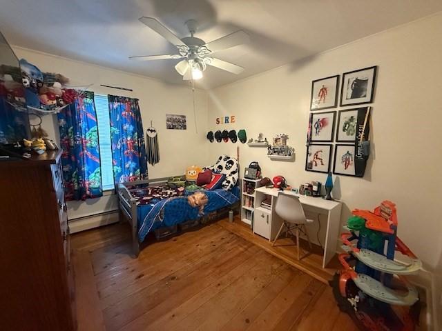 bedroom featuring ceiling fan, wood-type flooring, and a baseboard heating unit