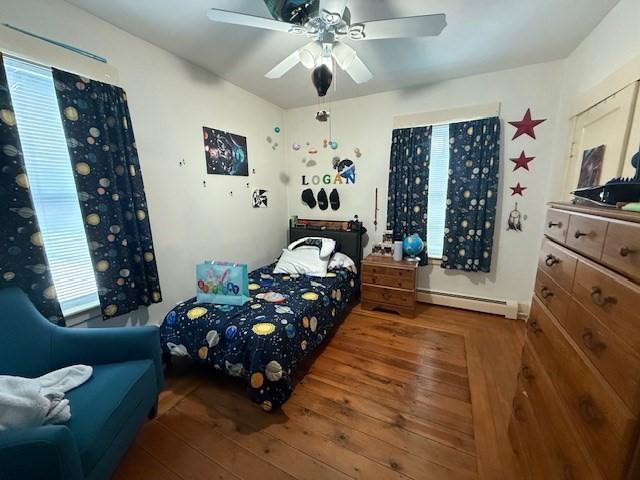 bedroom with a baseboard heating unit, wood-type flooring, and ceiling fan