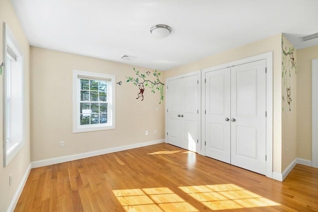 unfurnished bedroom with multiple closets and hardwood / wood-style floors