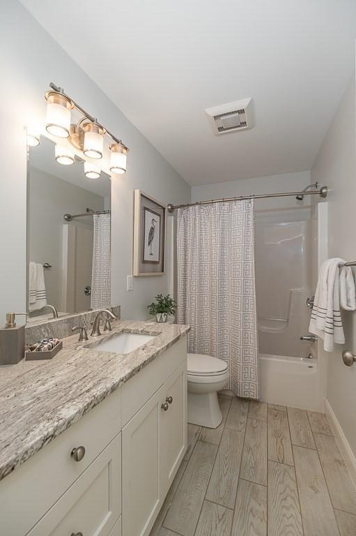 full bathroom with vanity, shower / bath combination with curtain, and toilet