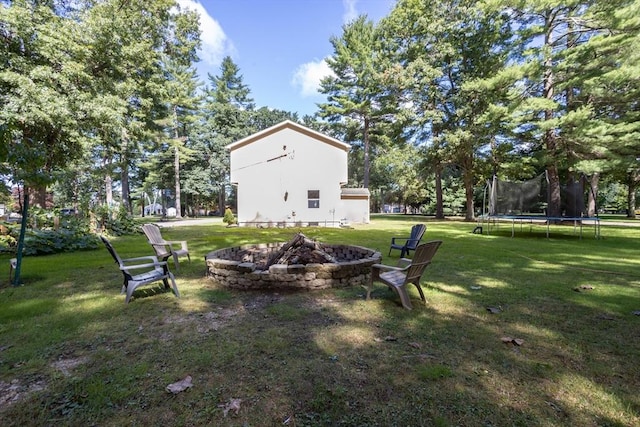 view of yard featuring a trampoline and a fire pit