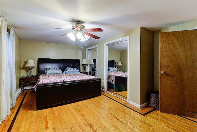 bedroom with ceiling fan, two closets, and hardwood / wood-style floors