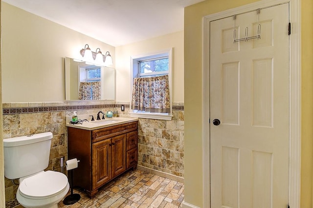 bathroom with tile walls, toilet, and vanity