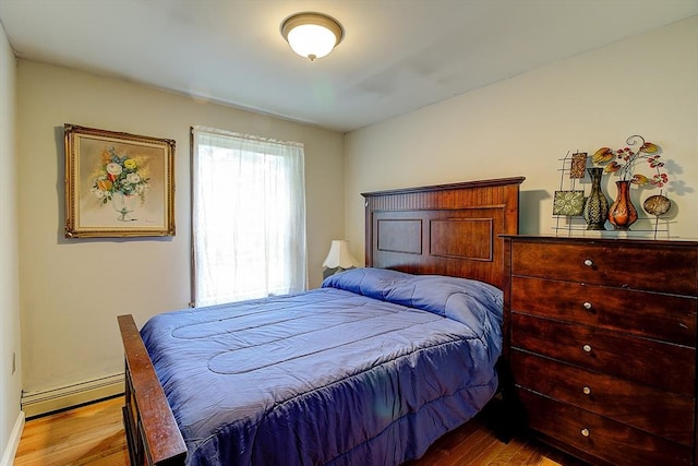 bedroom featuring hardwood / wood-style floors and a baseboard heating unit