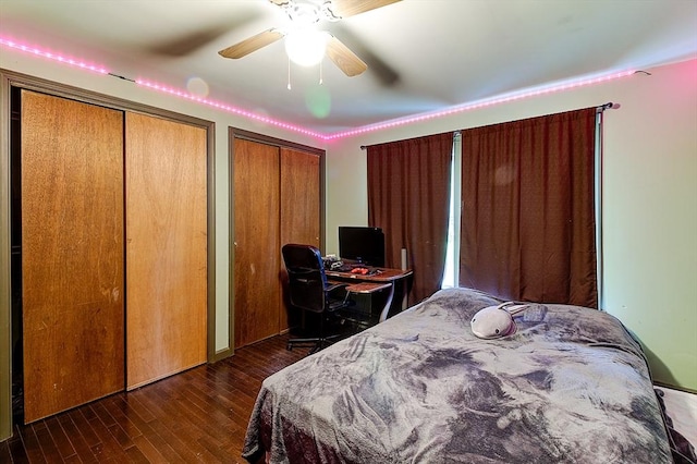 bedroom featuring dark wood-type flooring, ceiling fan, and two closets