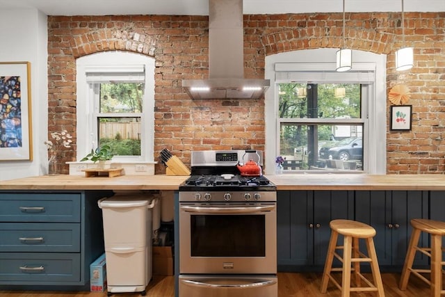 kitchen featuring wooden counters, gas range, ventilation hood, wood finished floors, and brick wall