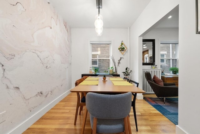 dining area with light wood finished floors and radiator