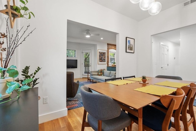 dining space with light wood-style floors, baseboards, ceiling fan, and a chandelier