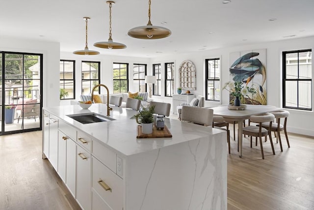 361 Walden Unit 361, Cambridge, MA 02138 - kitchen featuring light wood finished floors, decorative light fixtures, an island with sink, white cabinets, and recessed lighting