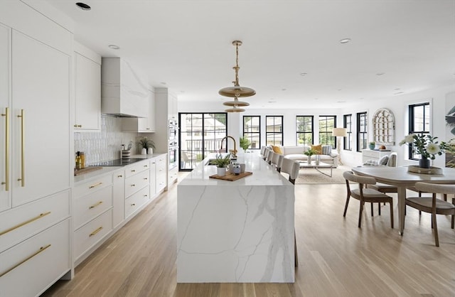 361 Walden Unit 361, Cambridge, MA 02138 - kitchen with wall chimney exhaust hood, double oven, light wood-style flooring, white cabinetry, and recessed lighting