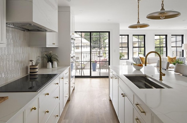 361 Walden Unit 361, Cambridge, MA 02138 - kitchen featuring range hood, black electric cooktop, decorative backsplash, wood finished floors, and hanging light fixtures