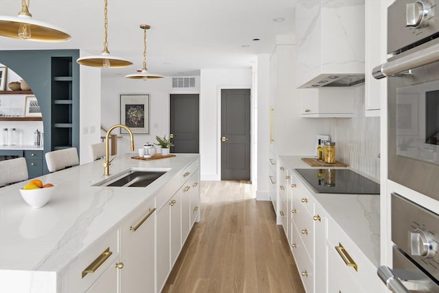 361 Walden Unit 361, Cambridge, MA 02138 - kitchen featuring black electric cooktop, custom exhaust hood, light wood finished floors, decorative light fixtures, and white cabinetry