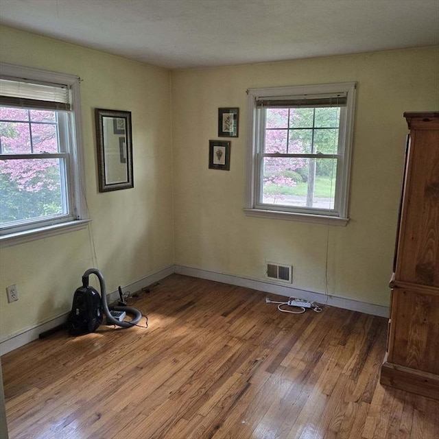 spare room featuring healthy amount of natural light, wood finished floors, and baseboards