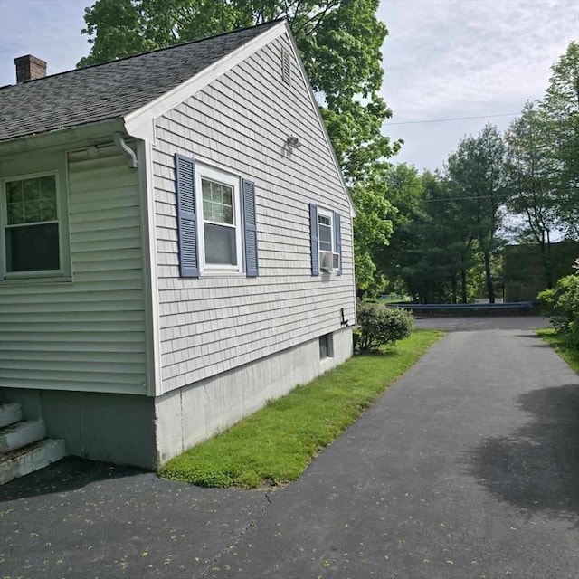 view of side of home with roof with shingles, a chimney, and cooling unit