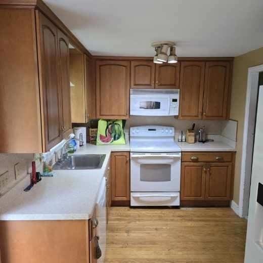 kitchen with white appliances, a sink, light countertops, and brown cabinetry