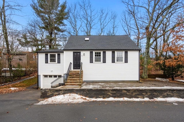 view of front of house featuring entry steps, driveway, an attached garage, and roof with shingles