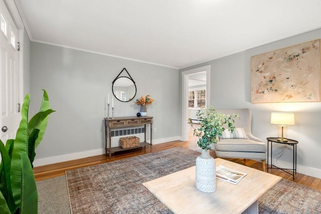 sitting room featuring crown molding, baseboards, and wood finished floors