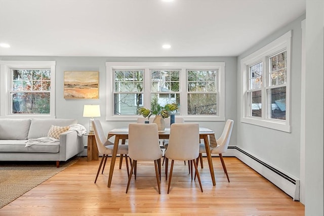 dining space with a baseboard heating unit, light wood-type flooring, and a wealth of natural light