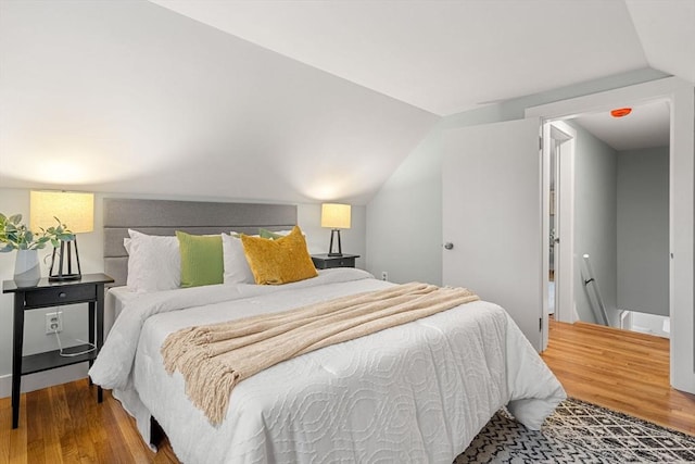 bedroom with wood finished floors and vaulted ceiling