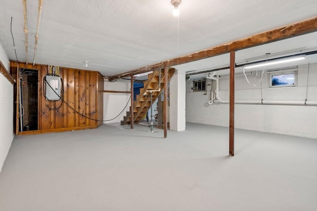 finished basement with wood walls, stairs, and concrete block wall