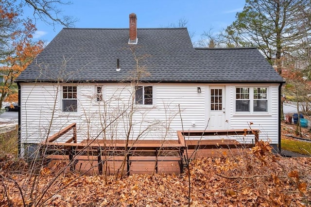 rear view of property featuring roof with shingles and a chimney