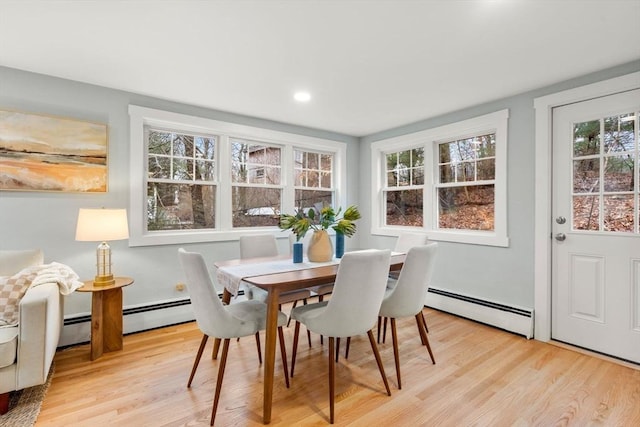 dining area with a baseboard heating unit and light wood-type flooring