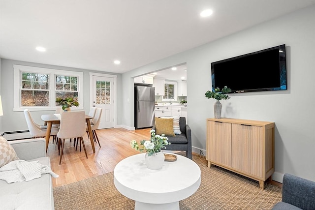 living area with a baseboard heating unit, recessed lighting, and light wood-type flooring