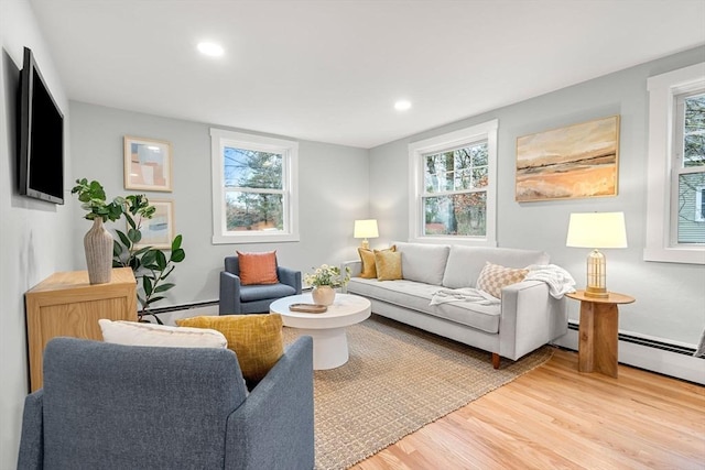 living area with recessed lighting, a baseboard heating unit, plenty of natural light, and light wood-style floors