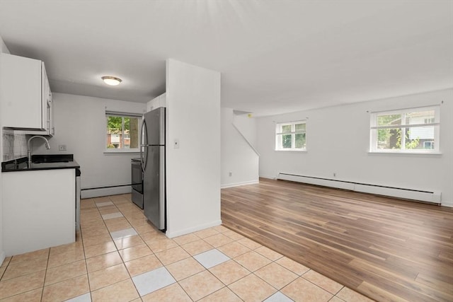 172 Bishop Dr Unit 172, Framingham, MA 01702 - kitchen with baseboard heating, stainless steel appliances, white cabinetry, open floor plan, and light wood-type flooring