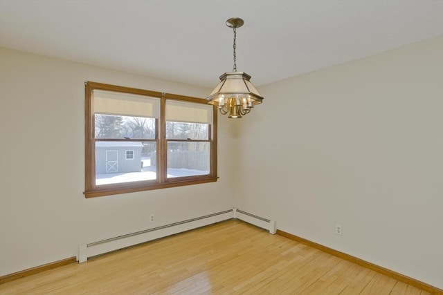 unfurnished room with hardwood / wood-style flooring, a notable chandelier, and a baseboard heating unit