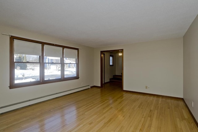 unfurnished room featuring a baseboard heating unit and light hardwood / wood-style floors