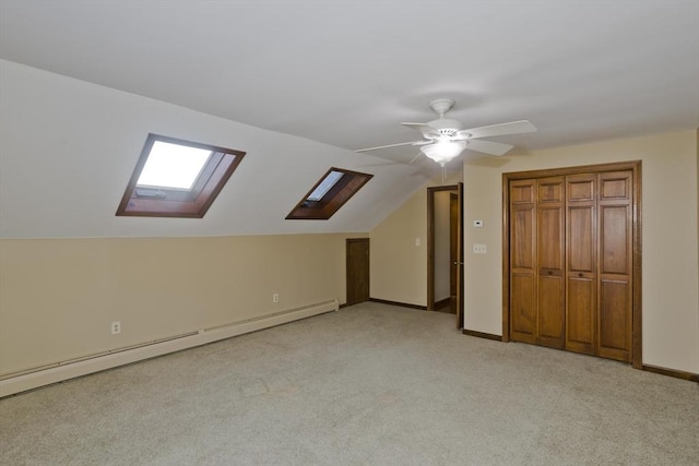 bonus room with light carpet, a baseboard heating unit, vaulted ceiling with skylight, and ceiling fan