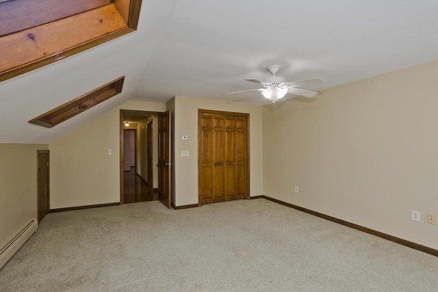 unfurnished bedroom featuring vaulted ceiling, light colored carpet, a baseboard radiator, a closet, and ceiling fan