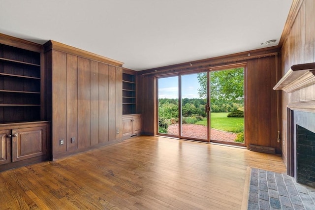 38 Bullard St, Sherborn, MA 01770 - unfurnished living room featuring wood walls, a fireplace with flush hearth, built in shelves, and wood finished floors