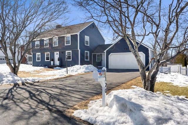 view of front of home with aphalt driveway, a chimney, an attached garage, and fence