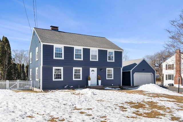 colonial home with a shingled roof, fence, a chimney, and an attached garage