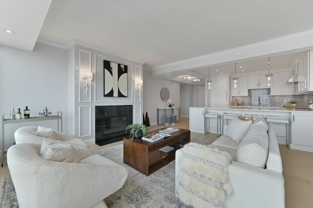 living room with sink, crown molding, and light hardwood / wood-style floors