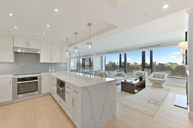 kitchen with white cabinetry, stainless steel oven, backsplash, and black electric cooktop