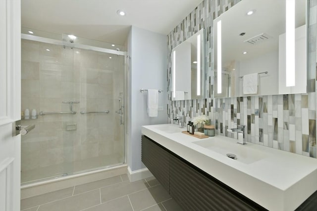 bathroom featuring tile patterned flooring, vanity, tasteful backsplash, and a shower with door